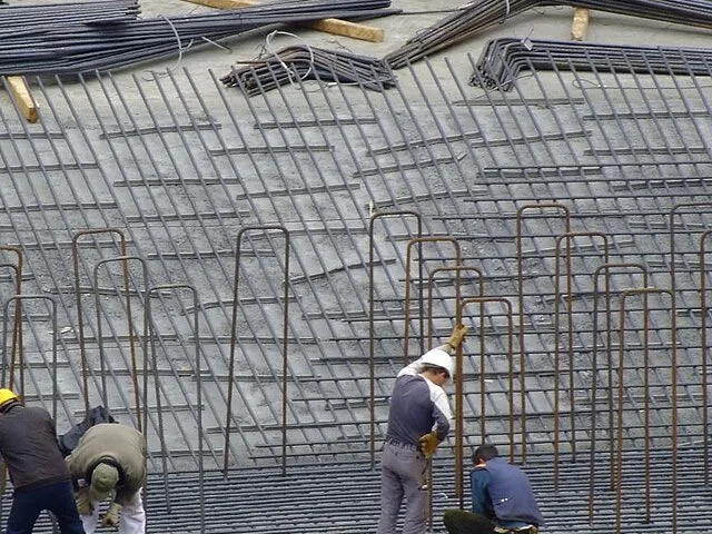 Betonacél-szerelők vasalják egy nagy felületű födém acélvázát az építkezésen
